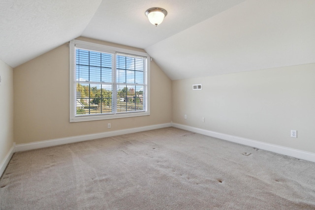 bonus room with light carpet and vaulted ceiling