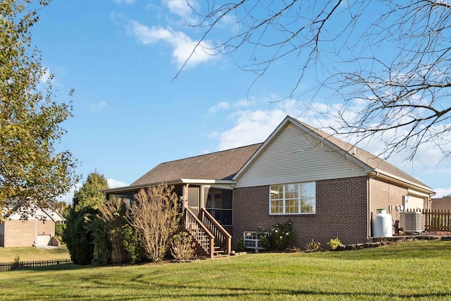 view of front of house featuring a front yard, central AC unit, and a sunroom