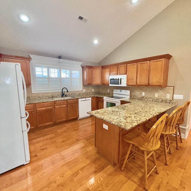 kitchen featuring kitchen peninsula, decorative backsplash, sink, and white appliances