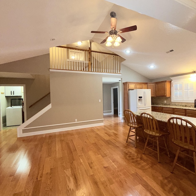 dining room featuring washer / dryer, light hardwood / wood-style floors, ceiling fan, and lofted ceiling