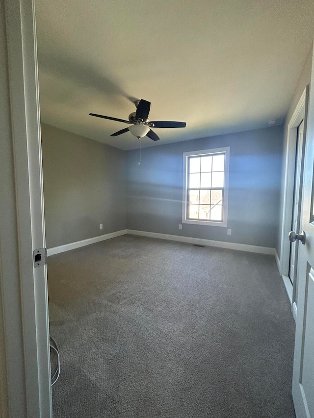 unfurnished room with dark carpet and ceiling fan