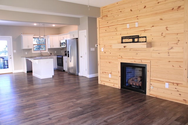 unfurnished living room with dark hardwood / wood-style flooring, sink, and wood walls