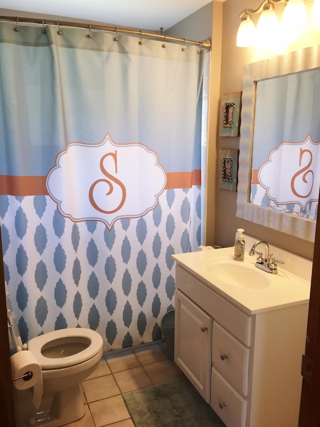 bathroom with toilet, walk in shower, vanity, and tile patterned flooring