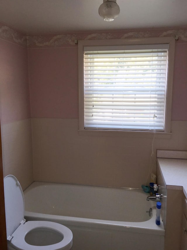 bathroom featuring vanity, toilet, and a tub to relax in