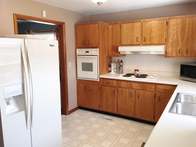 kitchen featuring backsplash, sink, and white appliances