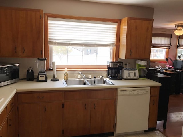 kitchen with white dishwasher, sink, backsplash, and ceiling fan