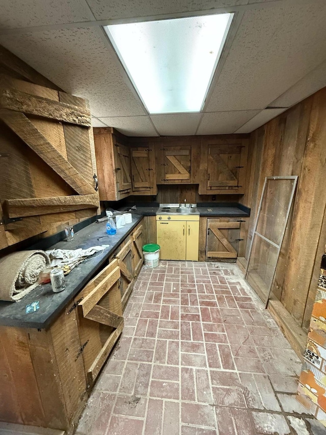 kitchen with a drop ceiling and wood walls