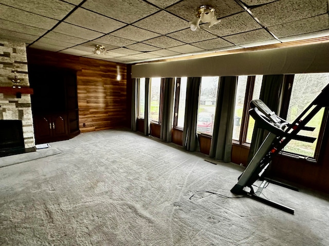 interior space with light carpet, ceiling fan, a fireplace, and wood walls