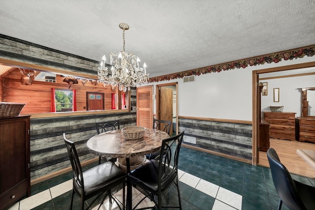 dining room with tile patterned floors, a textured ceiling, and wooden walls