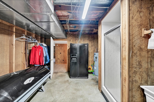 interior space featuring water heater, wood walls, and black fridge