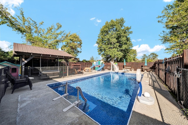 view of swimming pool with a water slide and a patio