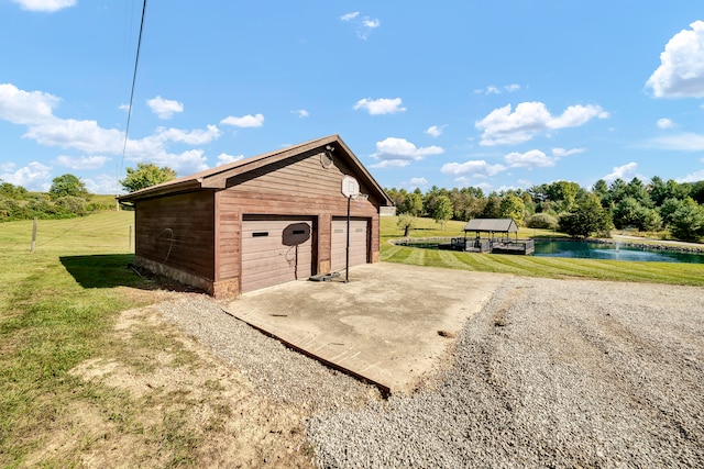 view of outdoor structure with a yard, a garage, and a water view