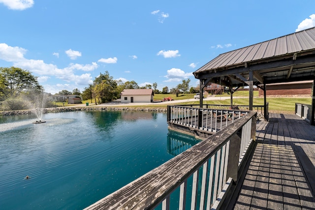 view of dock with a water view, a gazebo, and a lawn