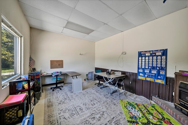 office space with a drop ceiling and wooden walls