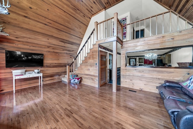 living room with wood walls, wood ceiling, hardwood / wood-style floors, high vaulted ceiling, and an inviting chandelier