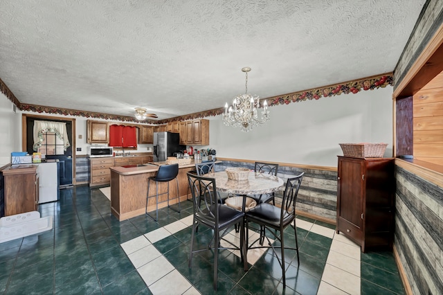 tiled dining area with a textured ceiling and ceiling fan with notable chandelier