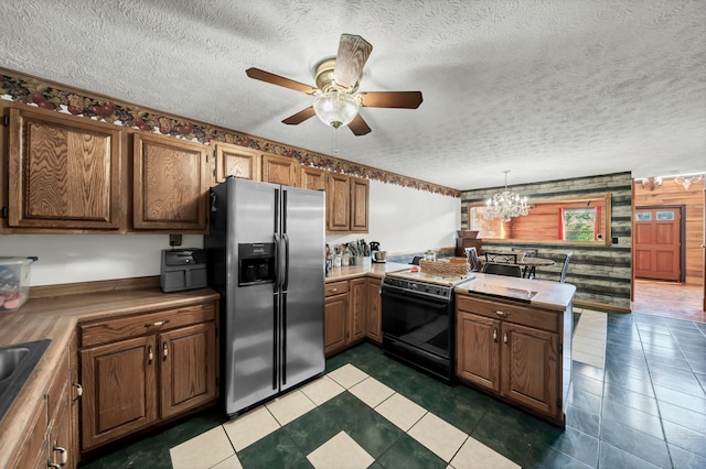 kitchen with black range with electric cooktop, wood walls, a textured ceiling, decorative light fixtures, and stainless steel fridge with ice dispenser