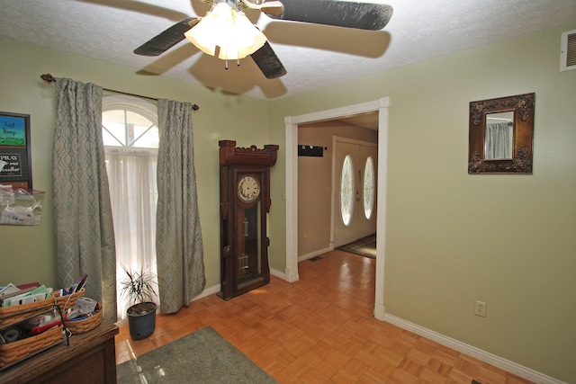 entryway with a textured ceiling, light parquet floors, and ceiling fan