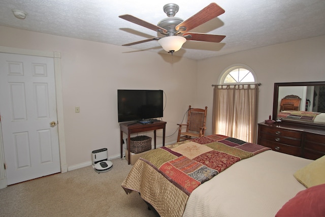 bedroom featuring a textured ceiling, light colored carpet, and ceiling fan