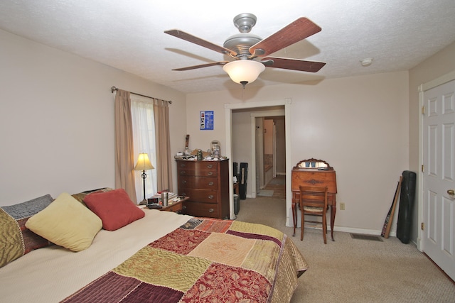 bedroom with a textured ceiling, light colored carpet, and ceiling fan