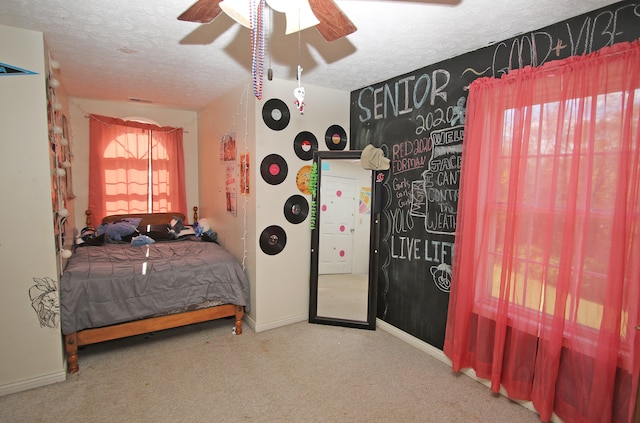 carpeted bedroom featuring ceiling fan and a textured ceiling