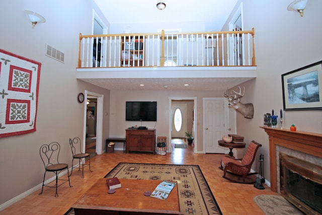 living room featuring a towering ceiling, light parquet flooring, and a tile fireplace