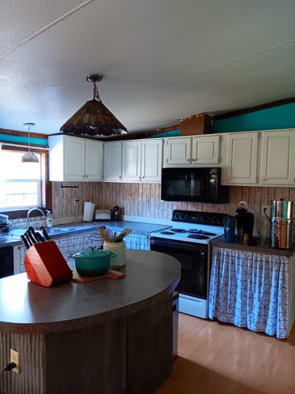 kitchen with electric range, white cabinetry, vaulted ceiling, light hardwood / wood-style flooring, and pendant lighting