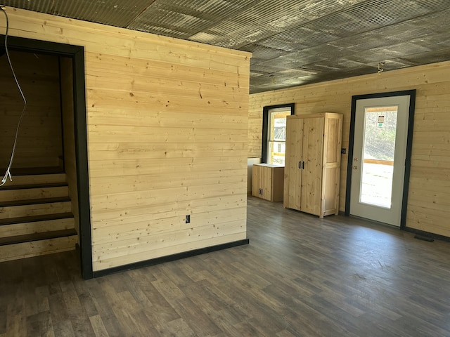 unfurnished room featuring wood walls, stairway, and dark wood finished floors