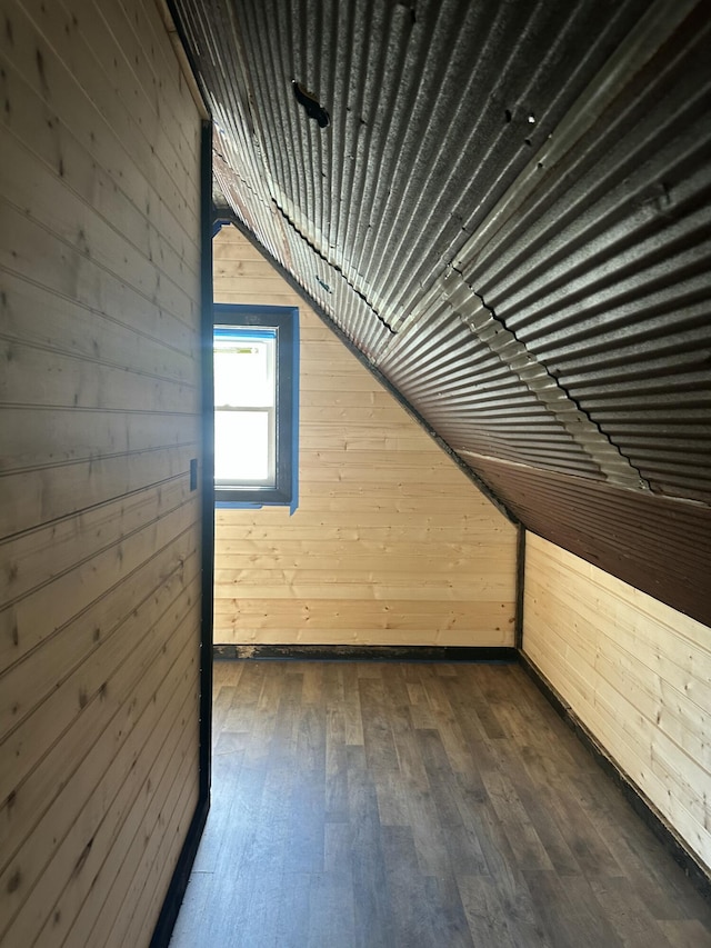 additional living space with dark wood-style floors, lofted ceiling, and wooden walls