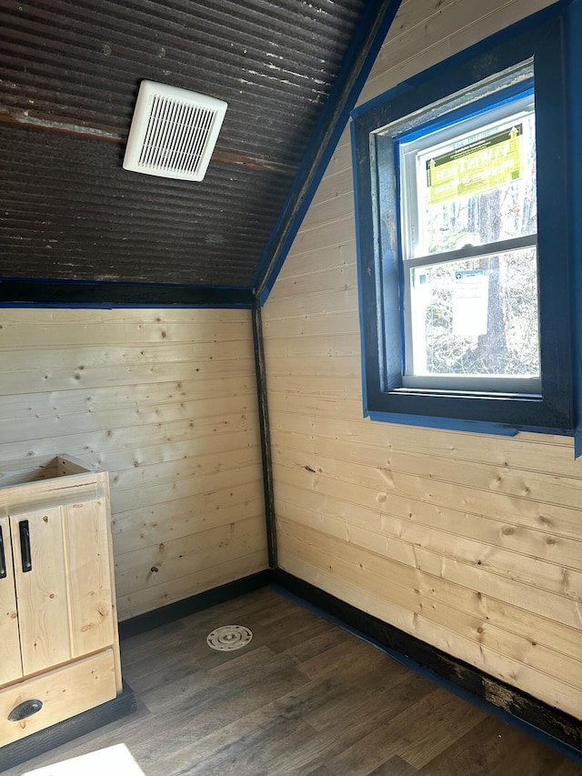 additional living space with lofted ceiling, wooden walls, visible vents, and dark wood-type flooring