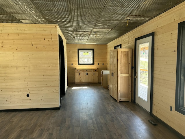 unfurnished room with wooden walls and dark wood-style flooring