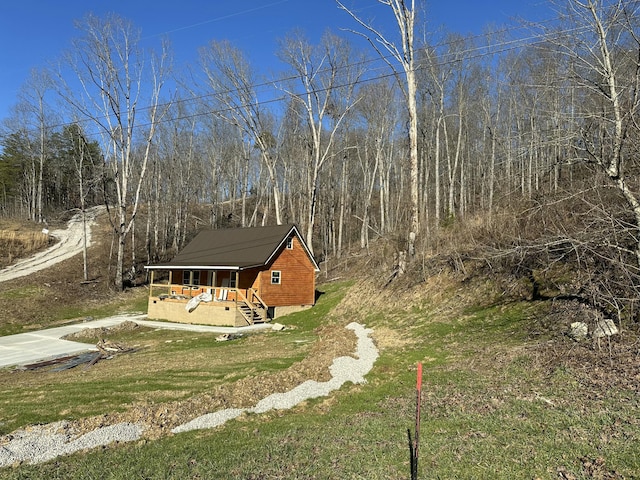 exterior space with a lawn, driveway, and a view of trees