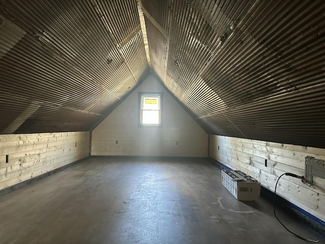 additional living space with vaulted ceiling, concrete floors, and concrete block wall