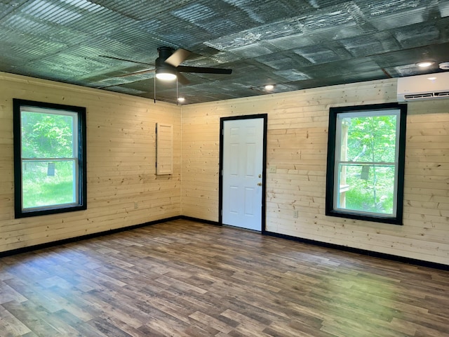 409 Freeman Branch Rd, East Bernstadt, KY 40729 - spare room featuring a wall mounted AC, a ceiling fan, wood finished floors, baseboards, and wood walls