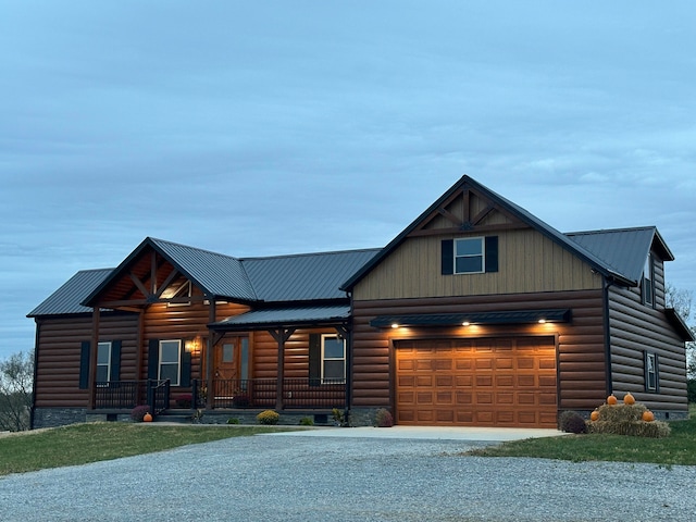 cabin with covered porch, a garage, and a front yard