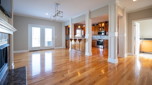 unfurnished living room with sink, crown molding, and light hardwood / wood-style flooring