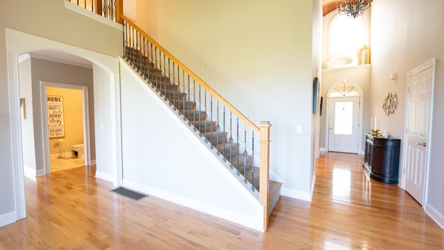 staircase featuring a towering ceiling and wood-type flooring