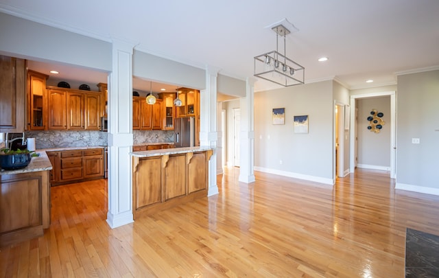 kitchen featuring tasteful backsplash, ornamental molding, pendant lighting, and light hardwood / wood-style floors