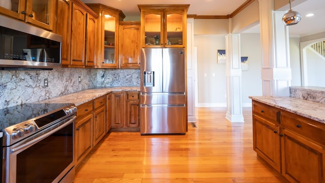 kitchen featuring light stone counters, light hardwood / wood-style flooring, backsplash, crown molding, and appliances with stainless steel finishes