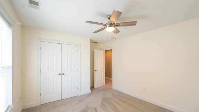 unfurnished bedroom with ceiling fan, light colored carpet, and a closet