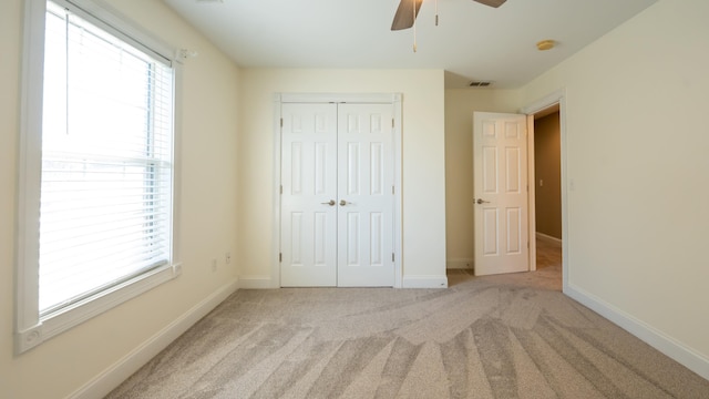 unfurnished bedroom with ceiling fan, a closet, and light colored carpet