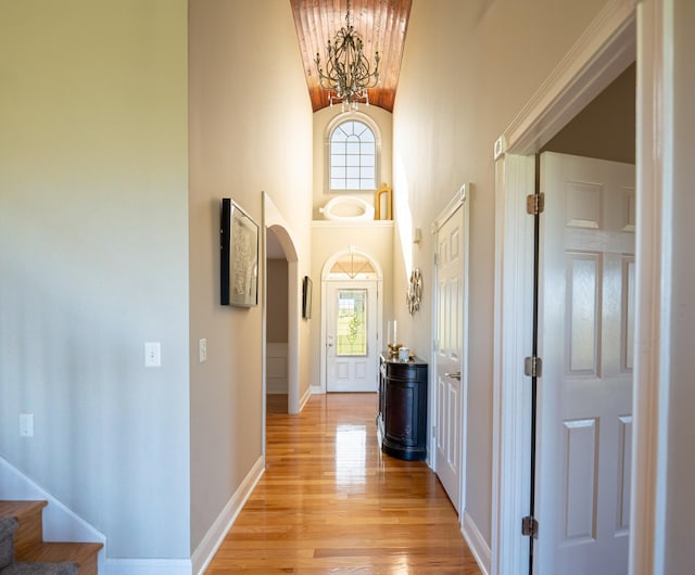 hall with a notable chandelier, light wood-type flooring, and high vaulted ceiling