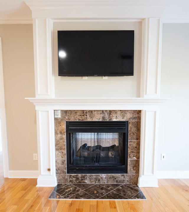 room details with a tile fireplace, ornamental molding, and hardwood / wood-style flooring