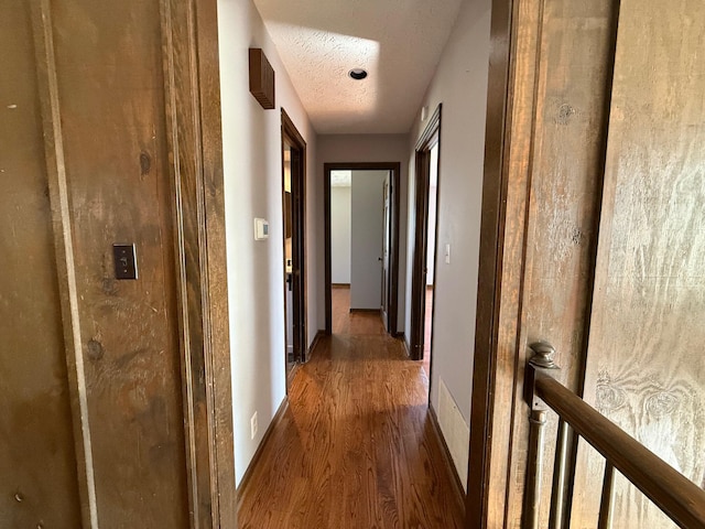 hall with a textured ceiling and dark wood-type flooring