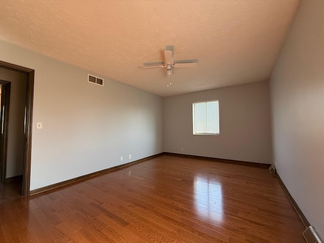 unfurnished room featuring dark wood-type flooring, a textured ceiling, and ceiling fan