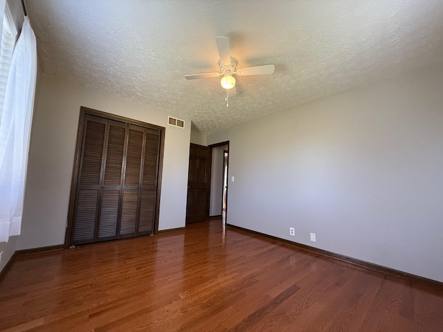 unfurnished bedroom featuring dark wood-type flooring, a textured ceiling, and ceiling fan