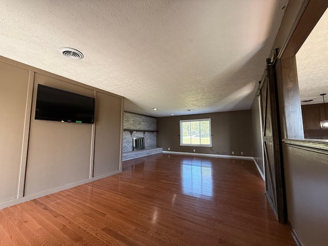 unfurnished living room with a textured ceiling and dark hardwood / wood-style flooring