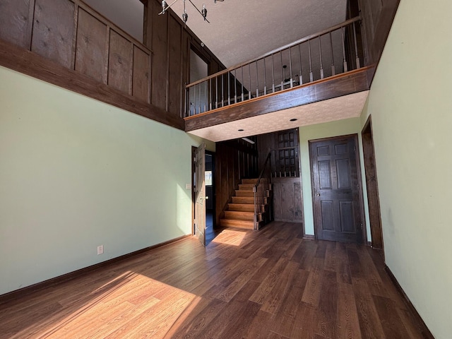 stairway featuring hardwood / wood-style flooring, a textured ceiling, and a high ceiling