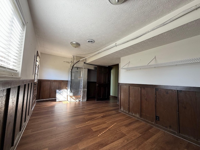 interior space with dark wood-type flooring, a textured ceiling, and wood walls