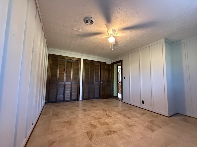 unfurnished bedroom featuring a textured ceiling, two closets, and ceiling fan